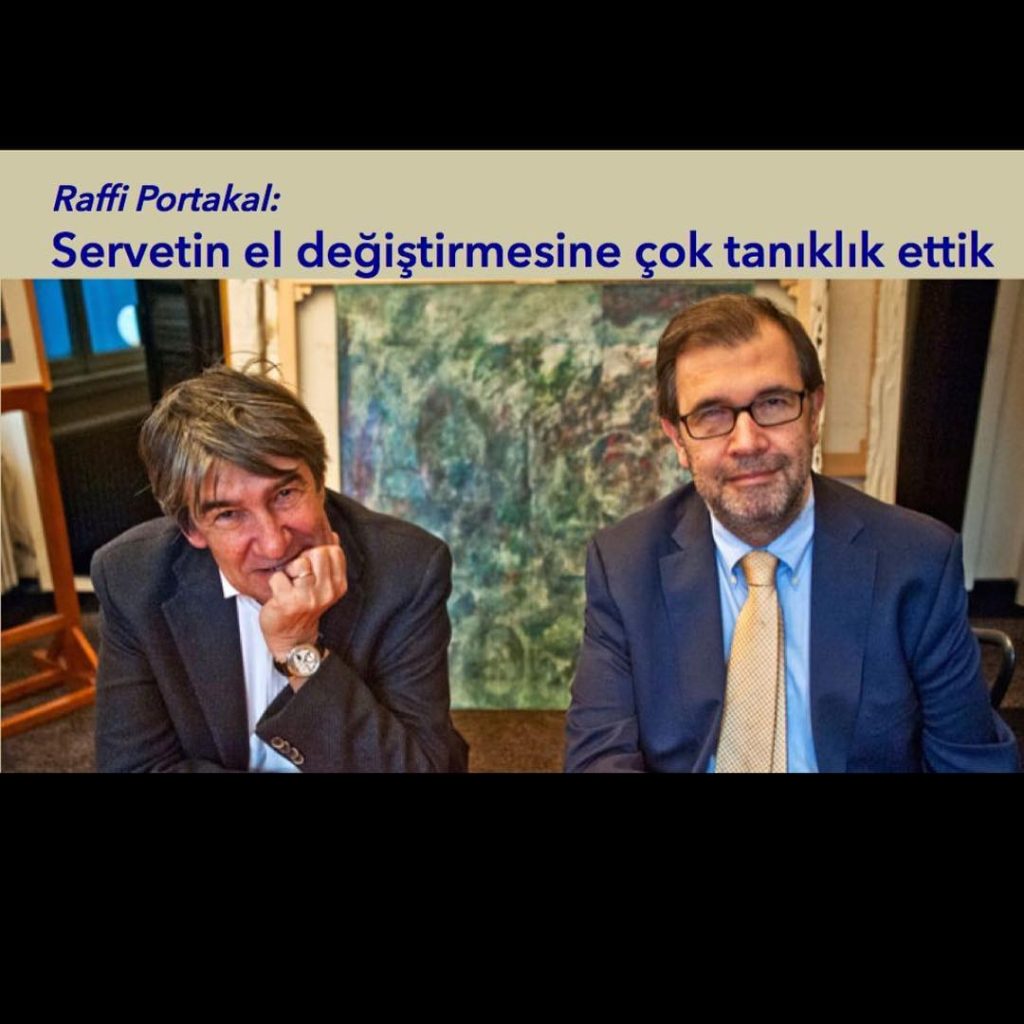 Two men in suits sitting side by side, engaged in conversation.