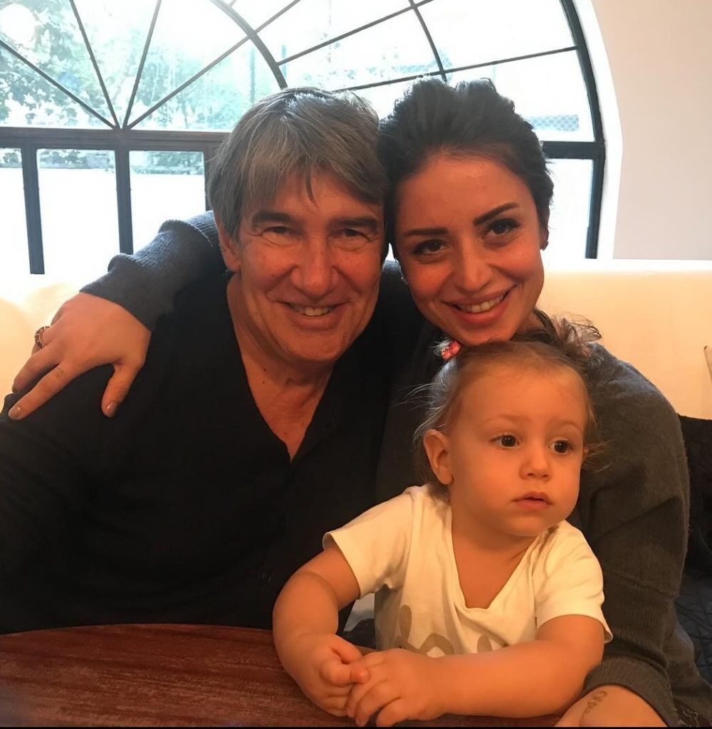 A man and woman sit at a table with a child, engaged in conversation and enjoying their time together.